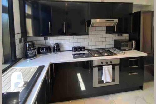 a kitchen with black cabinets and a stove top oven at Lovely 2 bedroom with private garden in Edinburgh