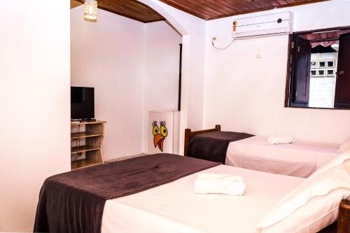 a hotel room with two beds and a tv at Pousada Bon Vivant in Porto De Galinhas