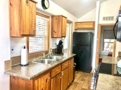 a kitchen with a sink and a black refrigerator at The Coyote Cabin - Cabins at Rim Rock in Austin