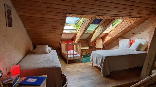 a attic room with two beds and a table at L'Hôt'Berge in La Chapelle-de-Brain