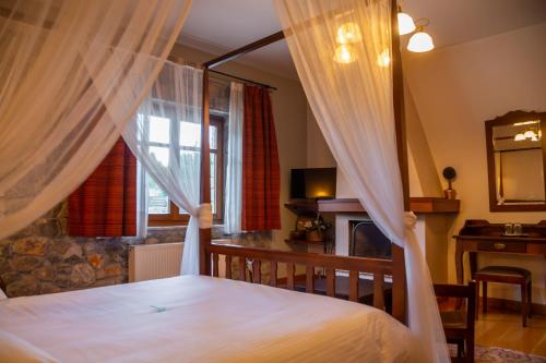 a bedroom with a bed with curtains and a fireplace at Karyatis Resort in Synikia Mesi Trikalon