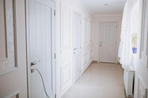 a white hallway with white doors and a white floor at Готель-спа "Еліт" in Kolʼchyno