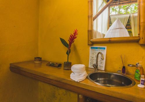 un bancone del bagno con lavandino e specchio di Minca Ecohabs Hotel a Minca