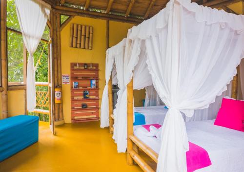 a bedroom with two beds with white curtains at Minca Ecohabs Hotel in Minca
