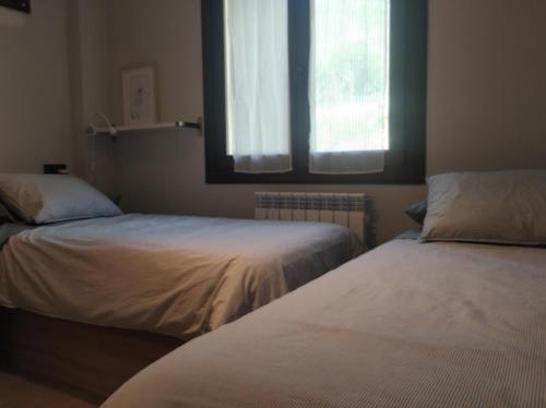 1 dormitorio con 2 camas y ventana en CHECK-IN CASAS La Tuca en Benasque