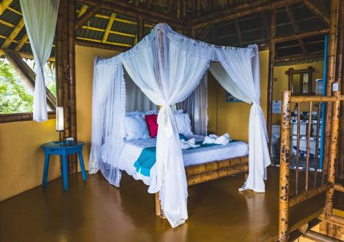 a bedroom with a canopy bed with white curtains at Minca Ecohabs Hotel in Minca