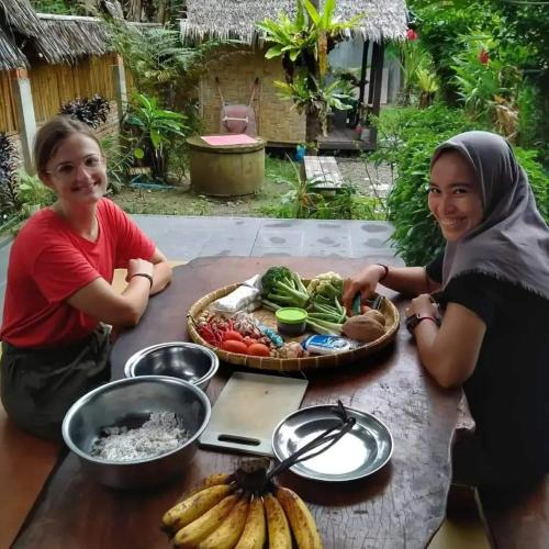 two women are sitting at a table with food at Sumatra Orangutan Discovery Villa in Bukit Lawang