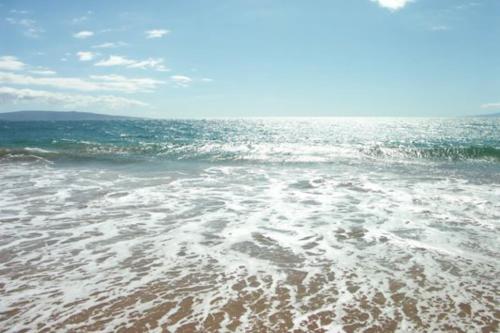 a view of the ocean with foam on the beach at Kihei Akahi in Wailea