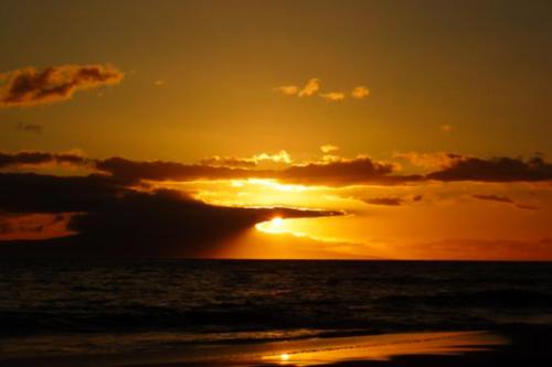 a sunset on the beach with the sun setting at Kihei Akahi in Wailea