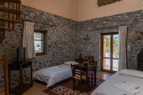 a bedroom with two beds and a tv and a window at Karyatis Resort in Synikia Mesi Trikalon