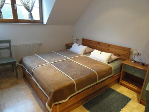 a bedroom with a large bed and a chair at Farm Stay Dolinar Krainer in Bohinjska Bela