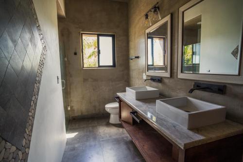 a bathroom with two sinks and a toilet at Surya Hotel in Valle de Guadalupe
