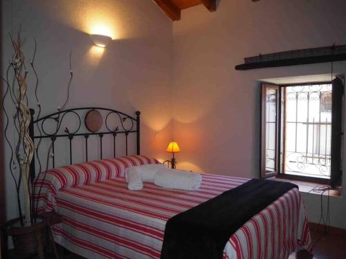 a bedroom with a bed with a red and white striped blanket at Casa Rural El Guindo in Avila