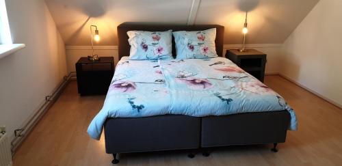 a bedroom with a large bed with a floral bedspread at Sfeervolle villa in Gasselte Drenthe bij Hemelriek in Gasselte