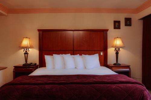 a bedroom with a large bed with two lamps on tables at Quinta del Rey Hotel in Toluca