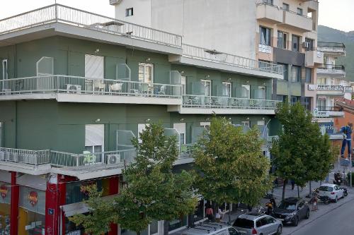 een groot groen gebouw met auto's geparkeerd op straat bij Hotel Orfeas in Xanthi