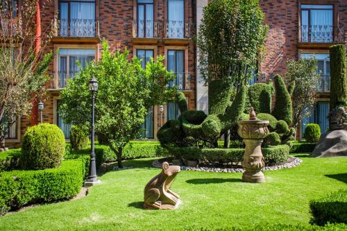 a garden with a statue in front of a building at Quinta del Rey Hotel in Toluca