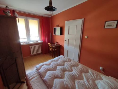 sypialnia z pomarańczowymi ścianami i łóżkiem w pokoju w obiekcie Apartament Helskie Trolle w HELU w mieście Hel