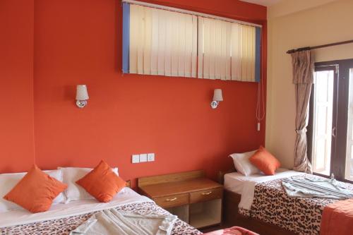 two beds in a room with orange walls at Jungle Wildlife Camp in Sauraha