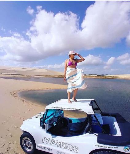 a woman standing on the roof of a car on the beach at Pousada Paracuru Surf in Paracuru