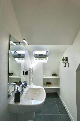 une salle de bain avec un lavabo et un miroir dans l'établissement La lucarne au centre ville avec parking privé et ascenseur, à Concarneau