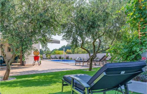a blue chair sitting in the grass next to a pool at Beautiful Home In Porec With Kitchen in Poreč