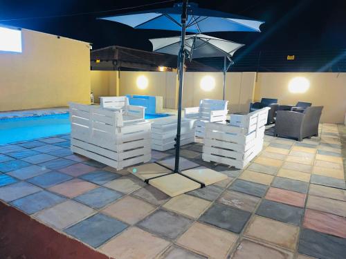 a patio with white furniture and an umbrella next to a pool at Druza’s guest house in Rustenburg