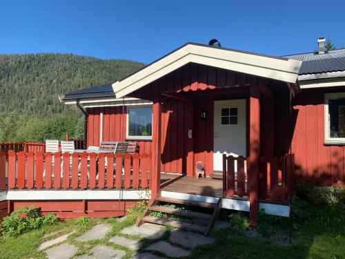 une maison rouge avec un chien assis sur une terrasse dans l'établissement Feriehus med utsikt til fjord og fjell, 