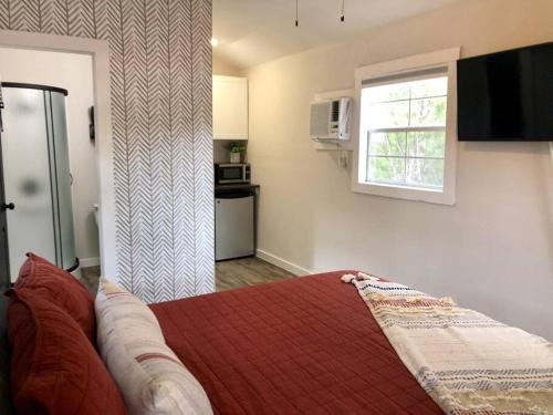 a bedroom with a bed with a red blanket and a window at The Fawn Cabin - The Cabins at Rim Rock in Austin