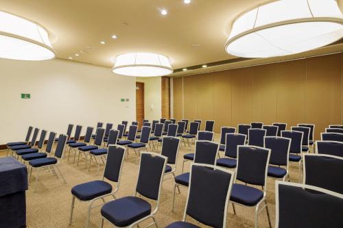a room with chairs and tables and chandeliers at Camino Real Santa Fe in Mexico City