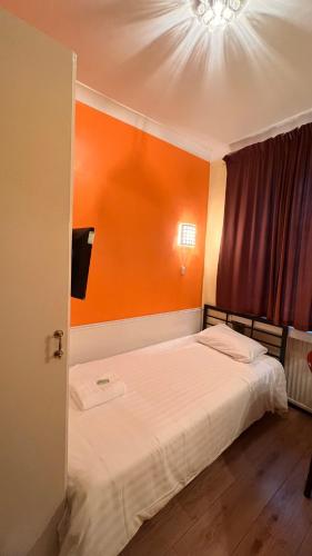 a bedroom with a bed with an orange wall at Gresham Hotel Bloomsbury in London