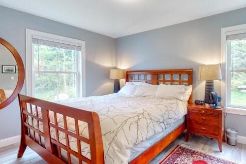 a bedroom with a bed with a wooden frame and two windows at Brown Moose Acres in Bridgton