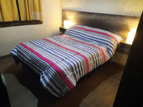 a bed with a striped comforter in a room at Cabaña El Manzano in Tunuyán