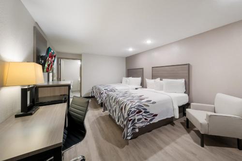 a hotel room with two beds and a flat screen tv at Red Roof Inn & Conference Center McKinney in McKinney