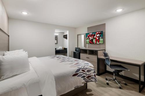 a bedroom with a bed and a desk with a computer at Red Roof Inn & Conference Center McKinney in McKinney