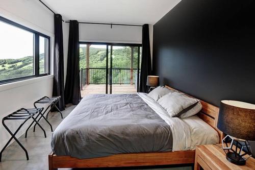 a bedroom with a large bed and a balcony at Blanc 24 - Les Chalets Alpins, Stoneham in Stoneham