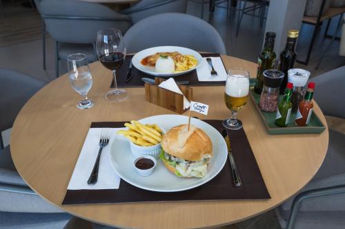 a table with a sandwich and french fries and glasses of wine at Slaviero Ponta Grossa in Ponta Grossa