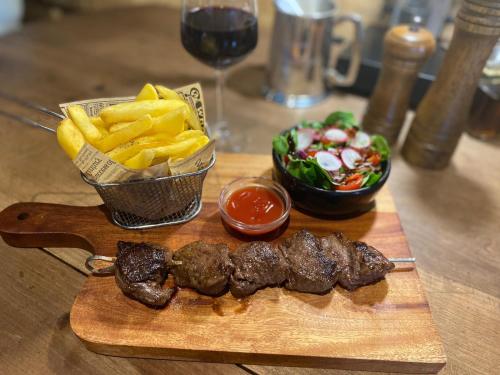 a cutting board with meat and french fries and a glass of wine at Le Relais D'Aulnay in Aulnay