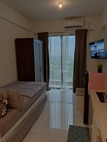 a bedroom with a bed and a tv and a window at Precious Angel Apartment Sky House BSD in Pagedangan