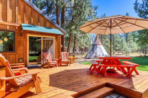 a wooden deck with a picnic table and an umbrella at Sisters Tollgate Retreat with Hot Tub & WiFi in Sisters