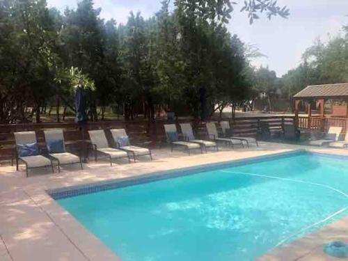 a large swimming pool with chairs and a gazebo at Fox Tiny Home - The Cabins at Rim Rock in Austin