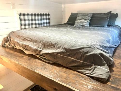 a bed sitting on a wooden bench in a bedroom at Fox Tiny Home - The Cabins at Rim Rock in Austin
