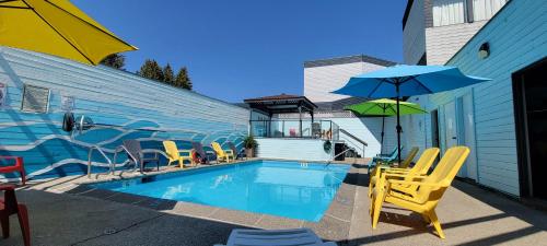 a pool with chairs and umbrellas next to a building at The Cedars Inn Hotel & Convention Centre in Gibsons