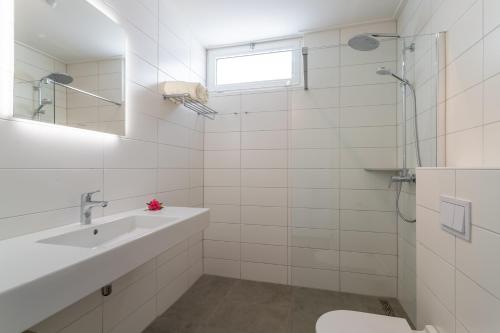 a white bathroom with a sink and a shower at Chogogo Dive & Beach Resort Bonaire in Kralendijk