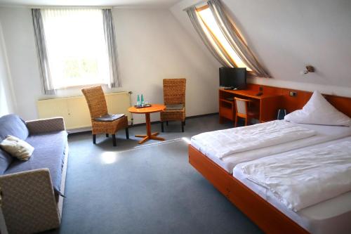 a bedroom with a bed and a desk and chairs at Pension Zur Harburg in Uslar