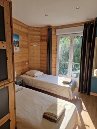 a bedroom with two beds and a large window at Le Syma, en plein centre ville in Le Bourg-dʼOisans
