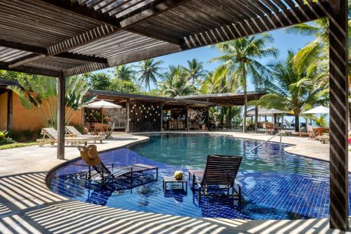 uma piscina num resort com cadeiras e palmeiras em Pousada Encanto da Lua em Barra Grande