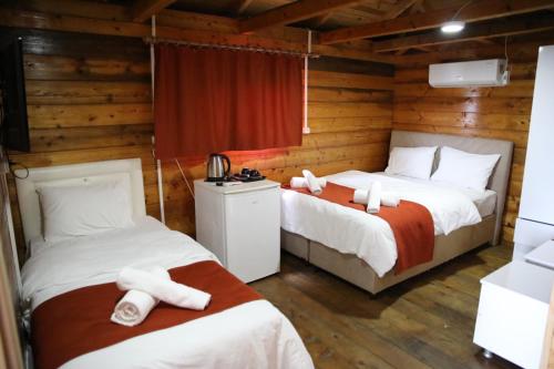 two beds in a room with wooden walls at Saklı Cennet Bungalow & Tatil Köyü in Çarşıbaşı