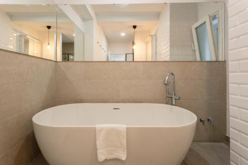a white bath tub in a bathroom with a mirror at MAREAS Family Home by Cadiz4Rentals in Cádiz