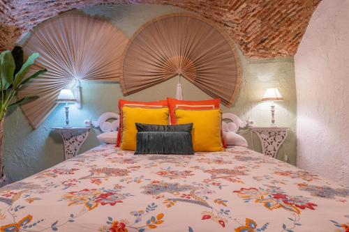 1 dormitorio con 1 cama grande con almohadas de color naranja y amarillo en AT La Habanera, en Cáceres